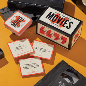 Brass Monkey Poorly Explained Movies Game box and cards on vibrant orange background for game night fun.