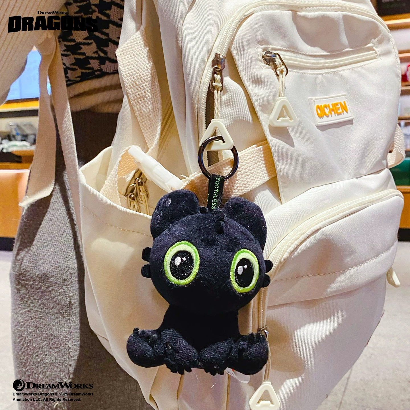 How to Train Your Dragon Toothless Plush Keychain attached to a white backpack, showcasing its cute design.