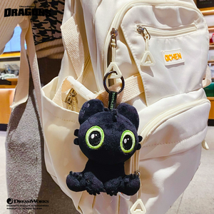 How to Train Your Dragon Toothless Plush Keychain attached to a white backpack, showcasing its cute design.
