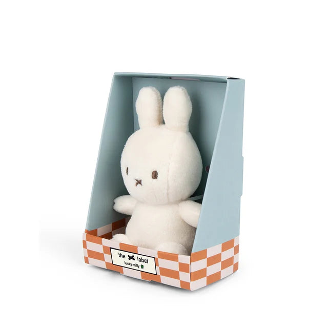 White plush bunny toy in a transparent box with a checkered base on a white background
