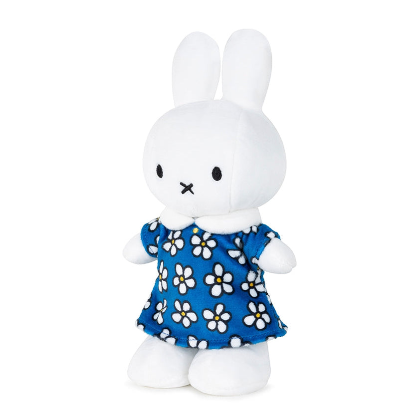 White plush toy rabbit wearing a blue dress with white flowers on a white background