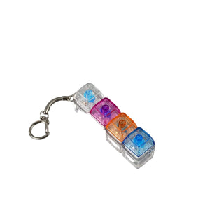 A small keychain accessory with four translucent plastic compartments in blue, purple, orange, and clear, attached to a silver metal lobster clasp, shown on a plain gray background.
