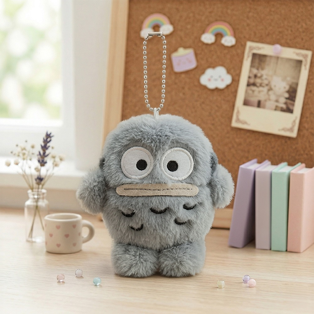 Sanrio Hangyodon Monochrome Plush Mascot Keychain Charm featuring a soft grey plush design on a wooden table.