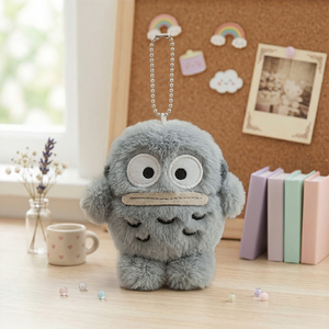 Sanrio Hangyodon Monochrome Plush Mascot Keychain Charm featuring a soft grey plush design on a wooden table.