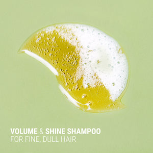 Shampoo bar with foam on a green background, labeled 'Volume & Shine Shampoo for fine, dull hair'.