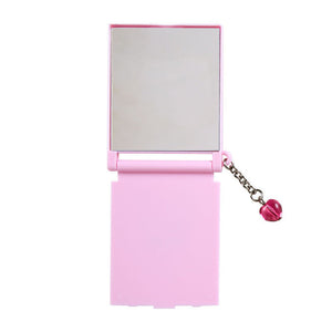 Pink compact mirror with a chain and bell on a white background