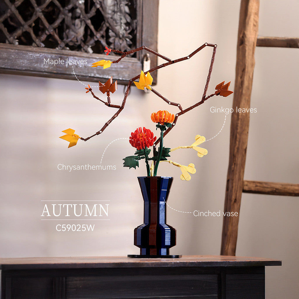 Decorative arrangement with branches labeled 'Maple leaves', 'Ginkgo leaves', and 'Chrysanthemums' in a blue vase on a wooden surface.