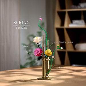 Decorative flower arrangement with a bamboo vase on a wooden surface, labeled 'Spring' and 'Daphne odorata'.