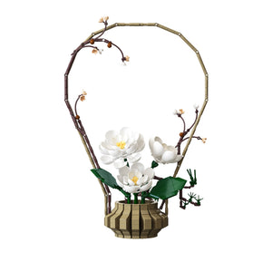 Decorative floral arrangement with white flowers and green leaves in a pot, set against a white background.