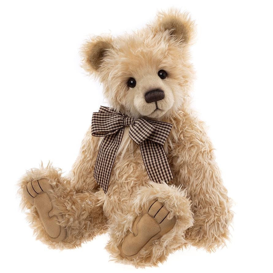 Beige teddy bear with a checkered bow tie on a white background