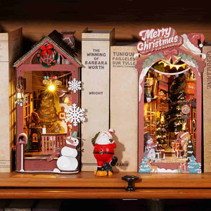 Decorative Christmas scene with a house, Santa Claus, and snowman on a wooden surface.