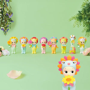 Colorful toy figures of animals with flower hats on a green background
