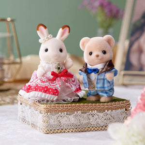Two toy animals, a rabbit and a bear, standing on a decorative box with a blurred background.