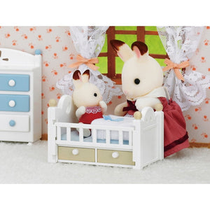 Two toy figures in a crib with a decorative background