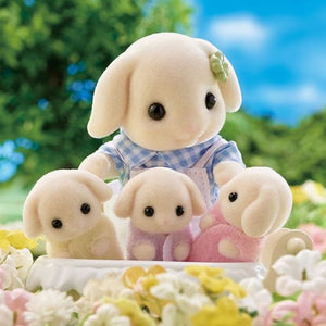 Plush toy lamb with three smaller lambs in a garden setting
