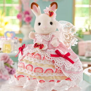 Toy rabbit in a pink dress with heart decorations on a cake-like platform.