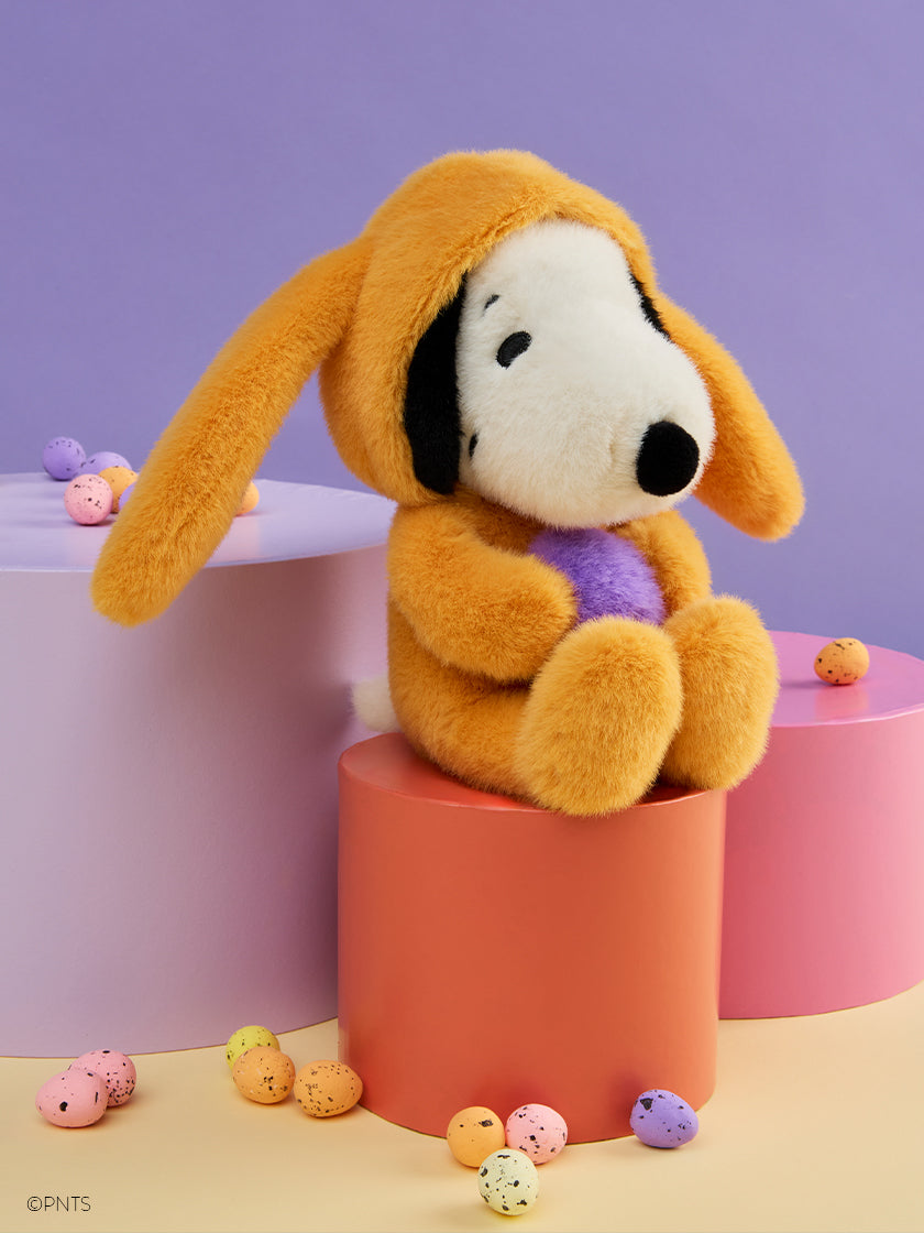Bon Ton Toys Peanuts Easter Snoopy ECO Fuzzy Yellow plush seated on colorful blocks surrounded by pastel eggs.
