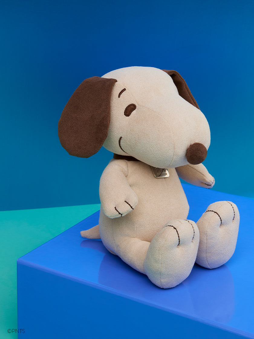 Bon Ton Toys Peanuts Limited Edition Snoopy Faux Suede Cream plush toy sitting against a blue background.