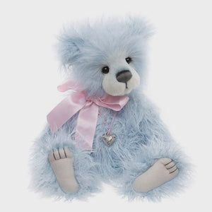 Blue teddy bear with a pink bow and heart charm on a white background