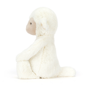 Jellycat Skipson Lamb plush toy sitting in profile with soft cream fleece and floppy ears.