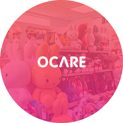 Pink plush toys with 'OCARE' logo in a store setting