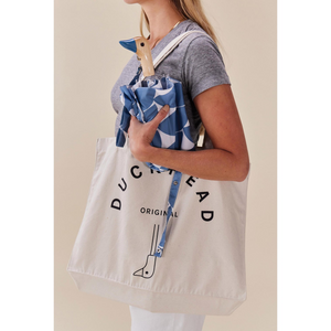Woman holding Original DuckHead Duck Umbrella Denim Moon inside a stylish canvas tote bag.