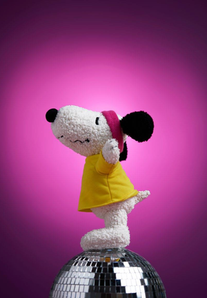 Peanuts Snoopy Flashbeagle plush toy in 80s dance outfit on a disco ball with a vibrant pink background.