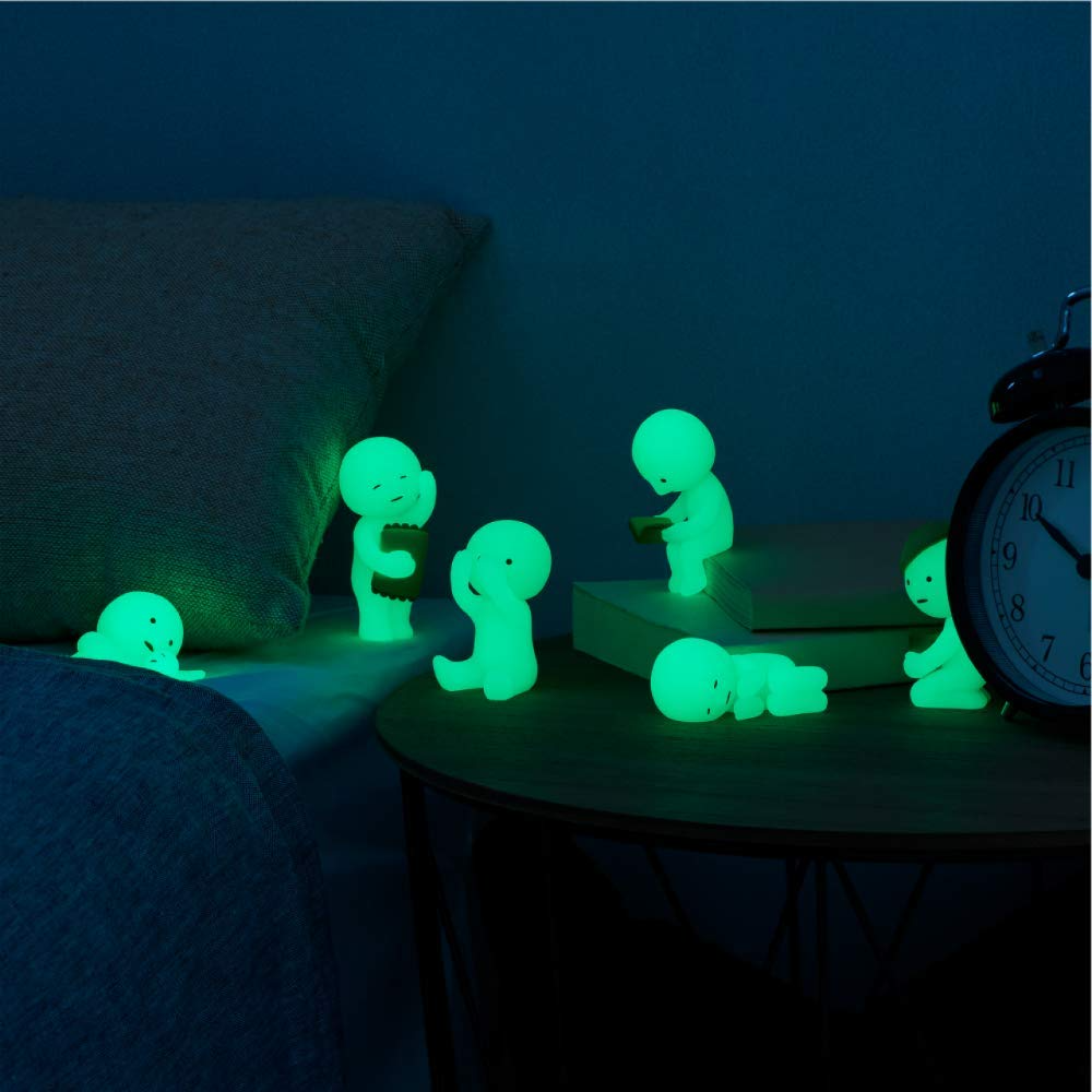 Glowing Smiski figures in a bedroom setting, showcasing their phosphorescent glow at night.