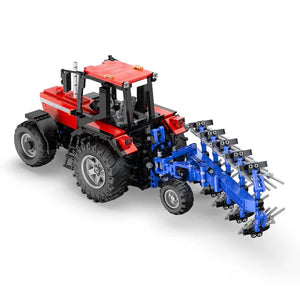 Toy tractor with red cabin and blue plow attachment on a white background