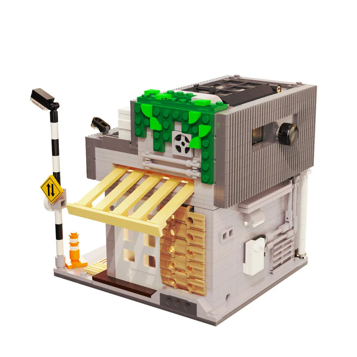 LEGO model of a small store with a green roof and yellow awning on a white background