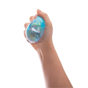 Hand squeezing the Discovery Zone Sparkly Squish Cube - Assorted, showcasing its glittery and stress-relieving features.