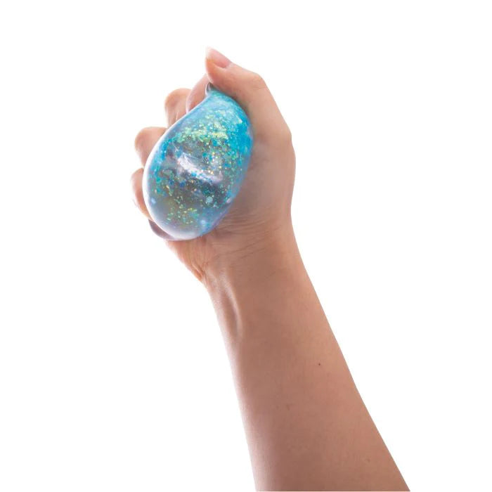 Hand squeezing the Discovery Zone Sparkly Squish Cube - Assorted, showcasing its glittery and stress-relieving features.