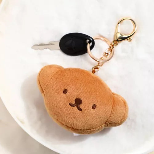 Plush keychain shaped like a bear on a white plate