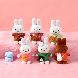 Set of small rabbit figurines with various accessories on a pink background