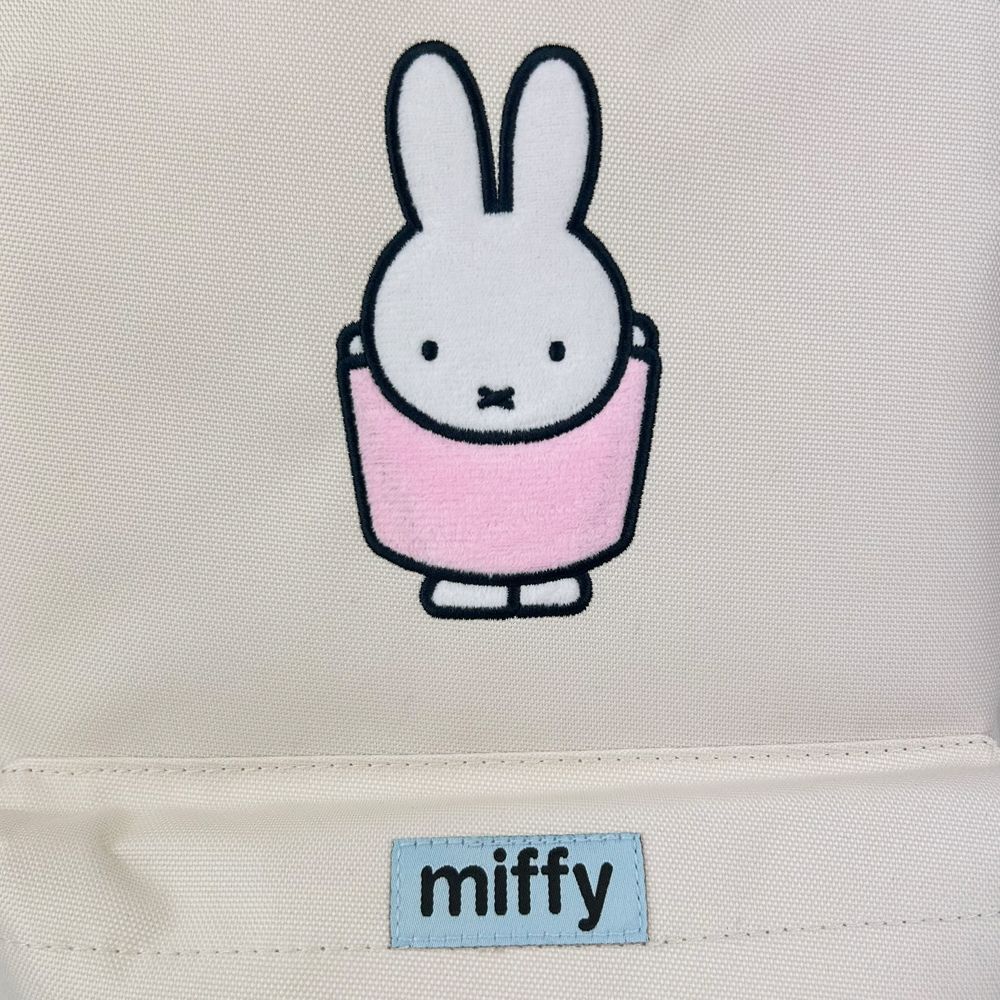 Embroidered rabbit character with a pink dress on a beige background, featuring the brand 'miffy'.