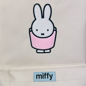 Embroidered rabbit character with a pink dress on a beige background, featuring the brand 'miffy'.