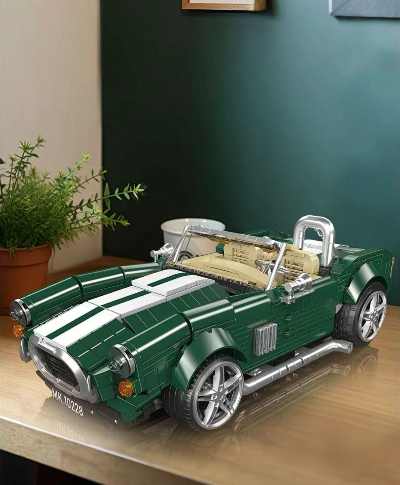 Model of a green convertible car on a wooden surface with a plant in the background.