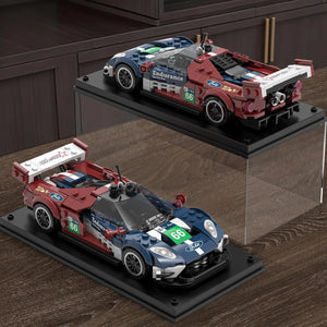 Two model racing cars on display stands with a wooden floor background
