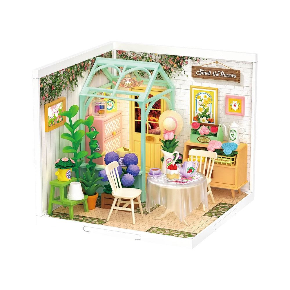 Miniature model of a cozy room with furniture and decor, featuring a table with flowers and chairs.