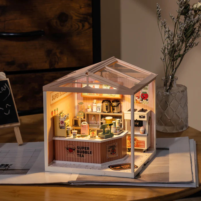 Miniature model of a bubble tea shop with interior details on a wooden surface.