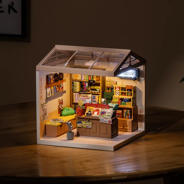 Miniature model of a store with books and furniture on a wooden surface.