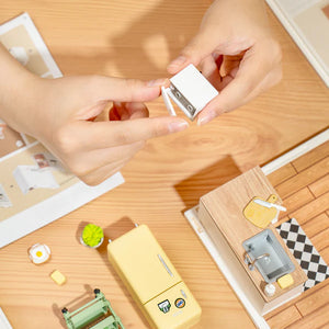 Small white sharpener being held by hands on a wooden surface with stationery items.