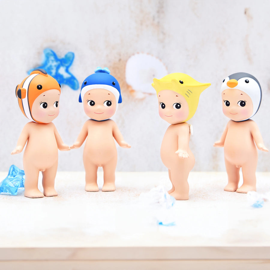 Four baby dolls with colorful hats on a light background