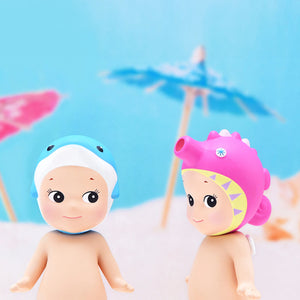 Two toy figures with colorful hats on a beach setting with umbrellas in the background.
