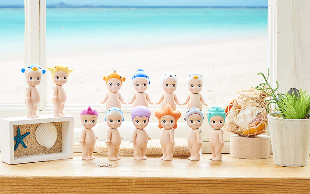 Set of small figurines on a windowsill with a beach scene outside