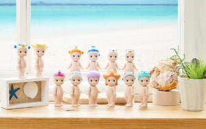 Set of small figurines on a windowsill with a beach scene outside