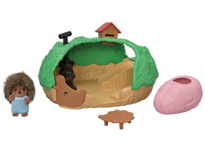 Toy set with a small house, hedgehog figure, and pink pot on a white background