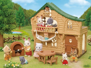Toy animal family around a wooden cabin in a garden setting