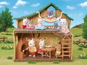 Toy wooden cabin with animal figures on a grassy field