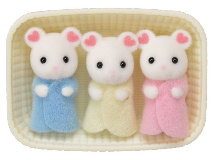 Three small plush toys in pastel outfits inside a woven basket.